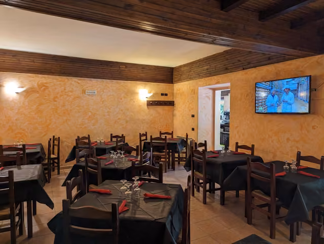Sala interna del Rifugio del Lupo a Scanno con tavoli, sedie e TV a parete