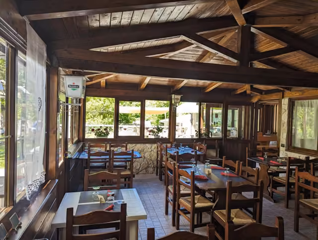 La sala del ristorante del Rifugio del Lupo a Scanno con tavoli in legno e finestre